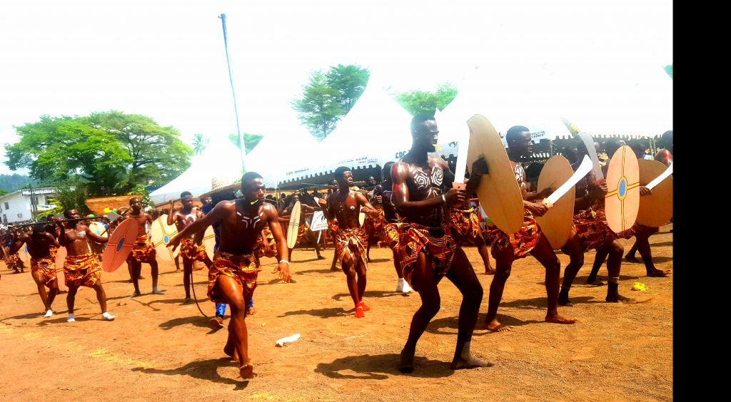 The Limbe Festival of Arts and Culture, FESTAC, on April 6, finally kicked off amidst tight security, following threats from separatist fighters, and an imposed lockdown on Fako Division. The ceremony that kicked off on Saturday, April 6, was chaired by the representative of the arts and culture minister, alongside the Governor Okalia of the Southwest region, and the Government Delegate to the Limbe City Council, Andrew Motanga, organiser of the arts and culture festival. This year’s FESTAC high point was the display of the rich and colourful carnival which showcased the major cultural settings and traditions of the many tribes that make up today’s Cameroon. Neighbouring countries to Cameroon, also displayed their cultural heritage at the FESTAC, drawing the admiration of onlookers. Talking at the event, the Limbe City Council delegate, Andrew Motanga harped on the issue of threats made against the organisation of the FESTAC. He maintained that the cultural festival is for the people, and has as main objective, the showcasing of the various rich cultures of the people of Cameroon, and that as such, everything will be done so as not to deprive the people, an opportunity of savouring their rich heritage. On his part, the Southwest Governor, Okalia Bilai harped on issues pertaining security in the town and region. The Governor implored the Limbe community to shun ghost towns and shutdowns advocated by pro-separatist activists and fighters. Fighters Brawl With Security operatives In the early hours of April 6, fighters surface on the Limbe road, and a gun scuffle ensued. The Amba fighters only retreated when the patrolling ESIR officers received backup from the BIR unit of the military force. A video released on social media showed the separatist fighters in the bushes shouting and challenging state security officers to enter the bushes for a fight. In the video, they claimed that they had inflicted casualties on state operatives, prompting them (ESIR unit) to call for backup. They claimed they can’t take the fight to the heart of the city because civilians will be the victims. Despite the confrontations in the early hours of that day, the festival still went on as planned, as security was beefed up in all corners of Limbe. Security checks were mounted at the festival ground, while police officers and gendarmes stationed at the entrance of the ceremony ground conducted deep security checks on all coming into the festival arena. FESTAC In Pictures