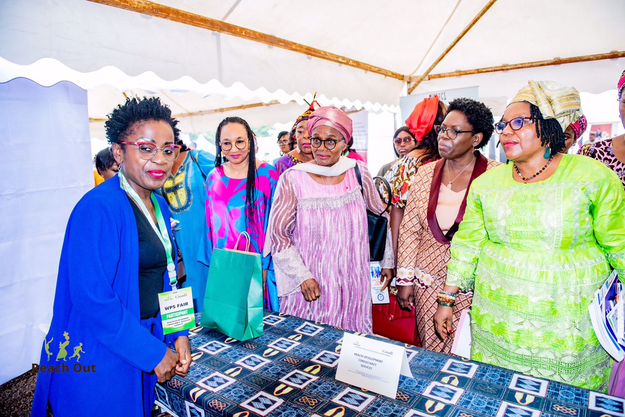 Minister, Reach Out Director look as woman exhibits her work