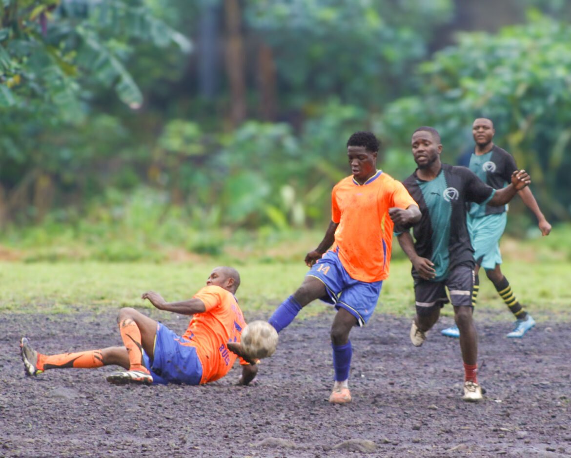 Young men battling for dominance on a muddy football pitch in Buea, keeping their community entertained